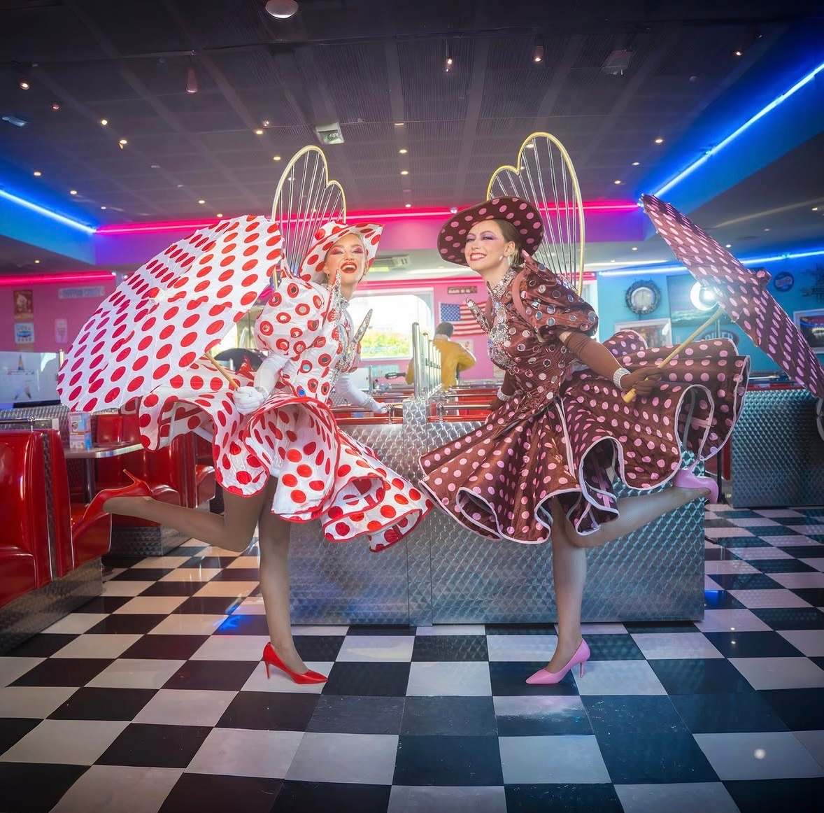 Deux artistes en robes à pois rouges, en mouvement sur un sol en damier