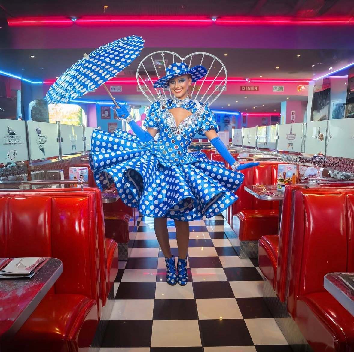 Artiste en robe à pois bleue et ombrelle assortie, dans un diner américain