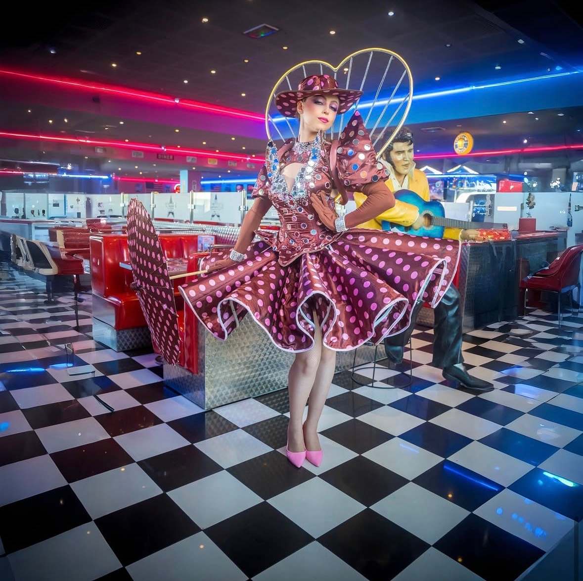 Artiste en robe à pois bordeaux et coiffe en forme de cœur, dans un diner américain