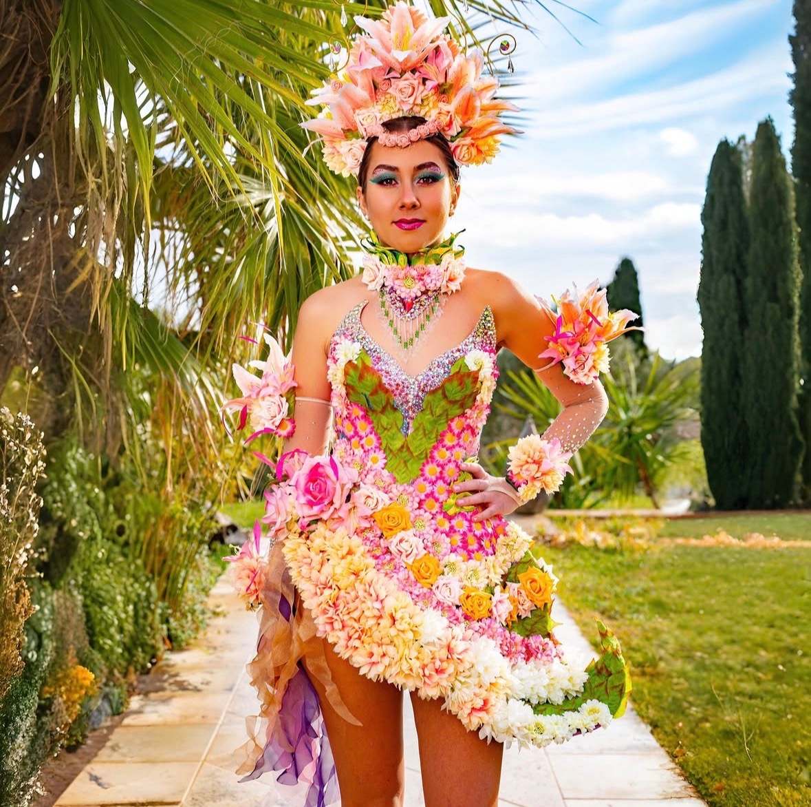 Robe et coiffe entièrement composées de fleurs roses et blanches, dans un jardin