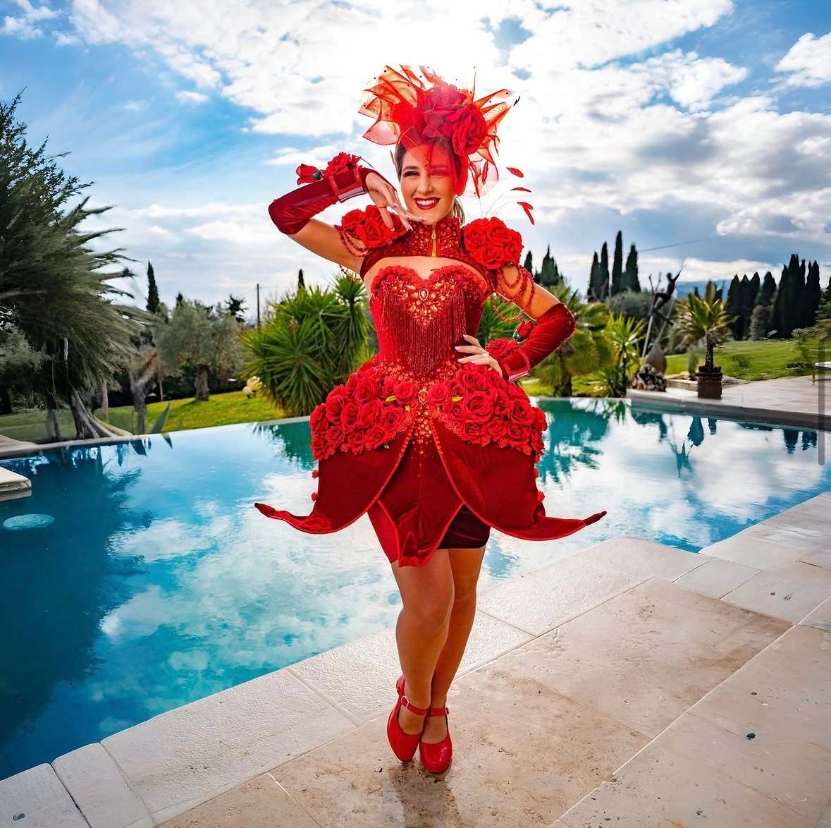 Robe rouge fleurie et coiffe de plumes, au bord d'une piscine