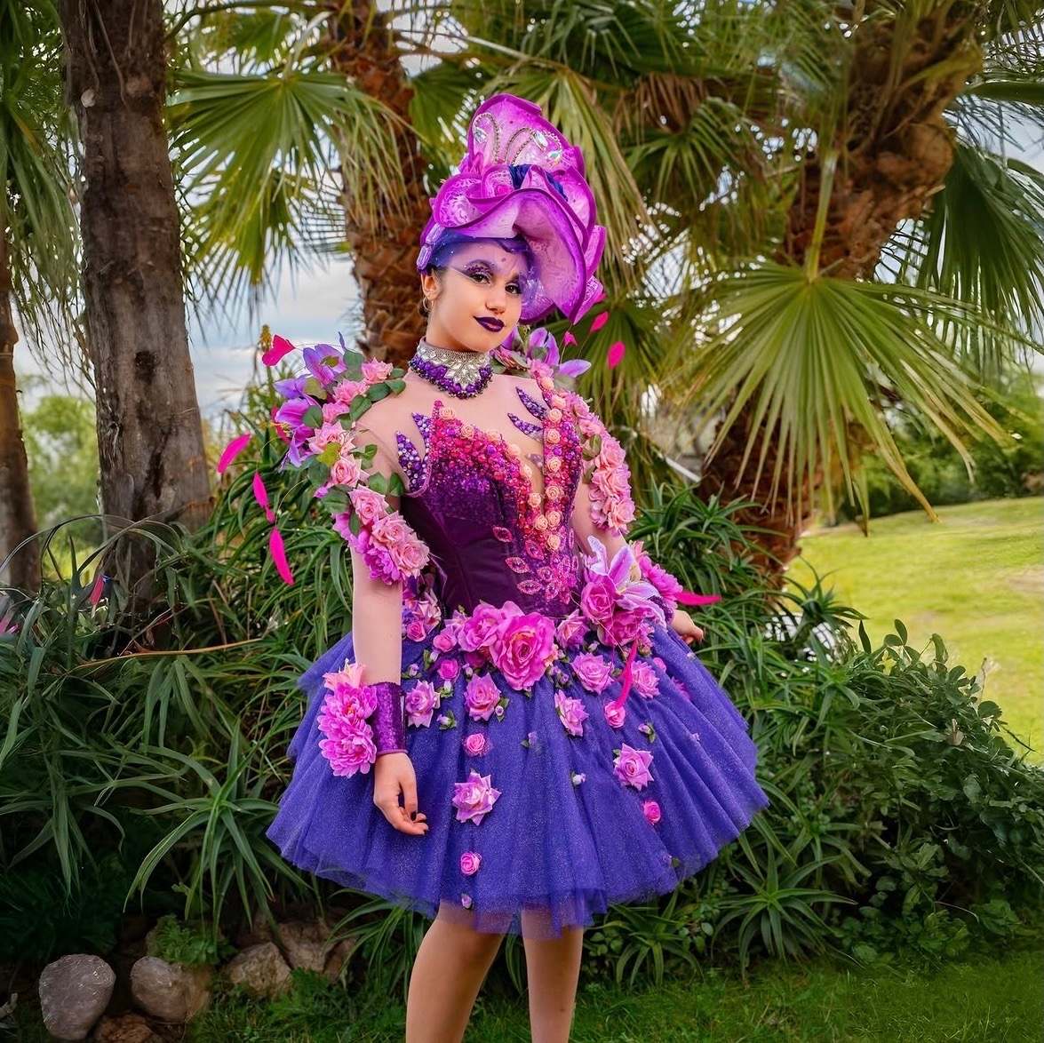 Robe violette fleurie et coiffe papillon, devant des palmiers
