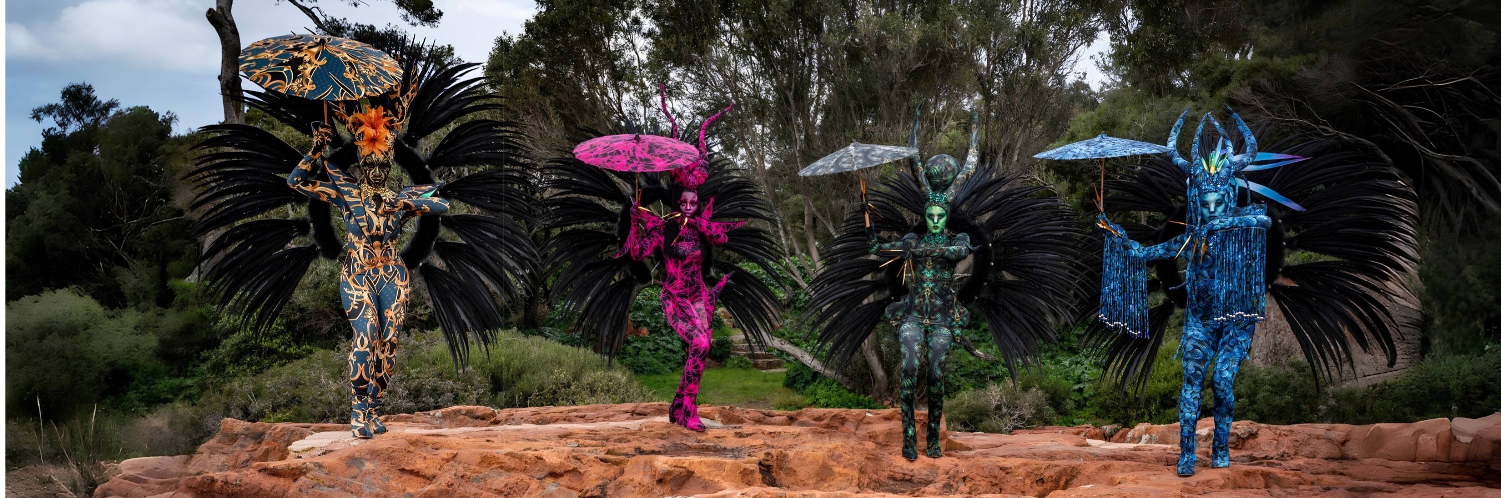 Quatre créatures costumées alignées en extérieur, ailes déployées