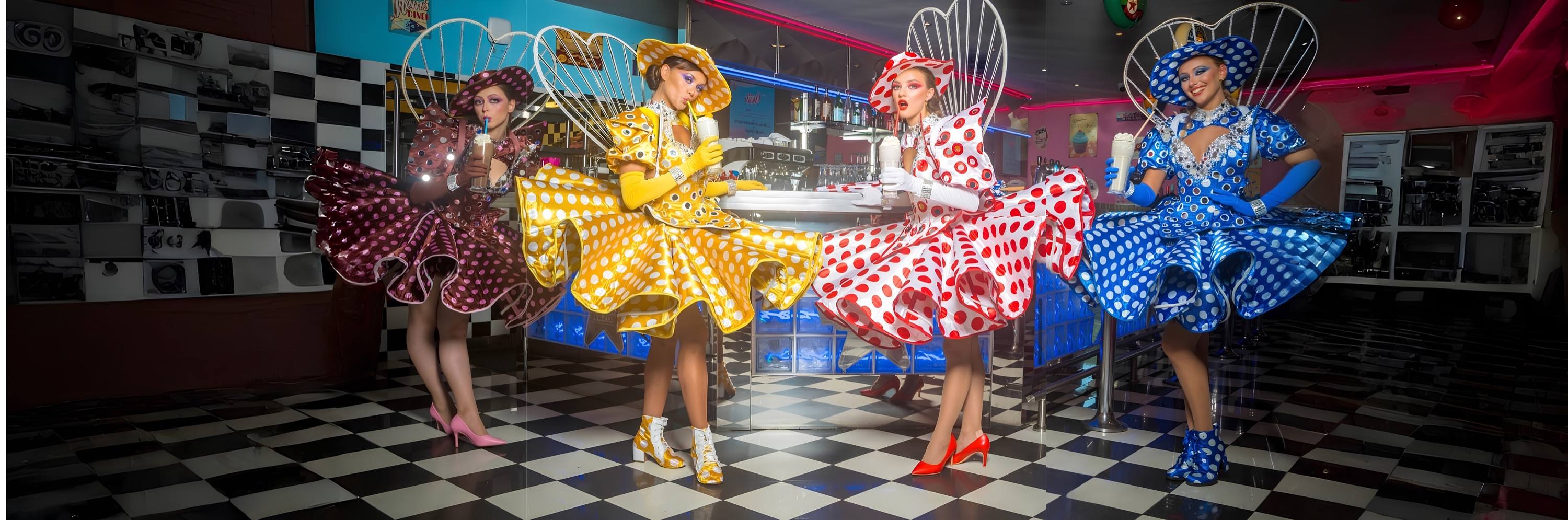 Quatre artistes pin-up en robes à pois dans un diner américain