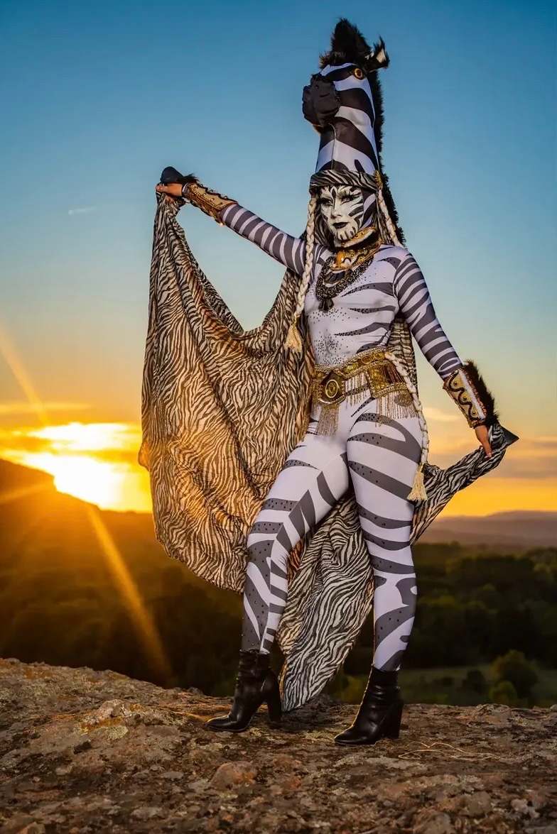 Artiste en costume de zèbre, voile ouvert, montagnes en arrière-plan